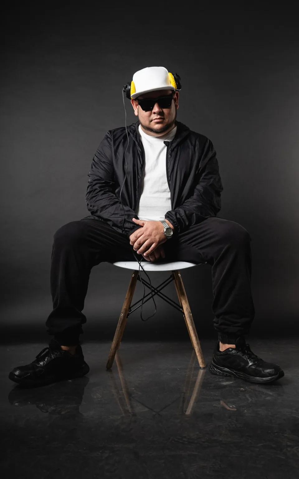 Sentado con audífonos y gorra blanca